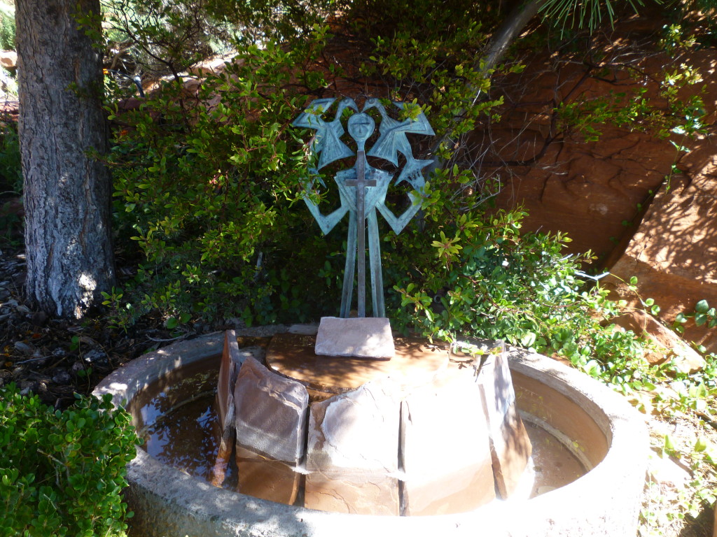 Small metal St Francis figure holding metal birds above an oak barrel fountain