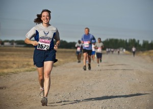 A smiling woman running a race with other runners behind her