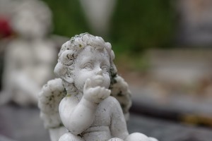 An angel child statue, blowing away something from before its mouth, as in blowing away a dandelion