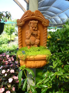 A statue of Pan playing his pipes, in a garden of greenery and flowers
