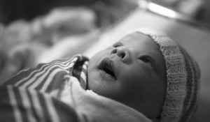 A newborn baby staring upwards with a look of wonder, openmouthed