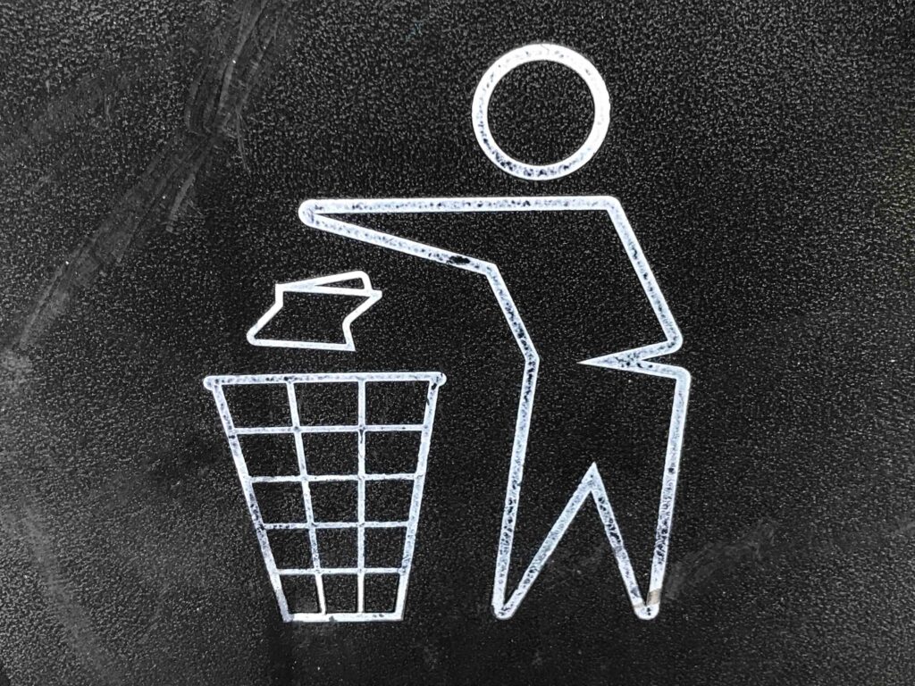 Black and white drawing of a human figure dropping trash into a wastebasket