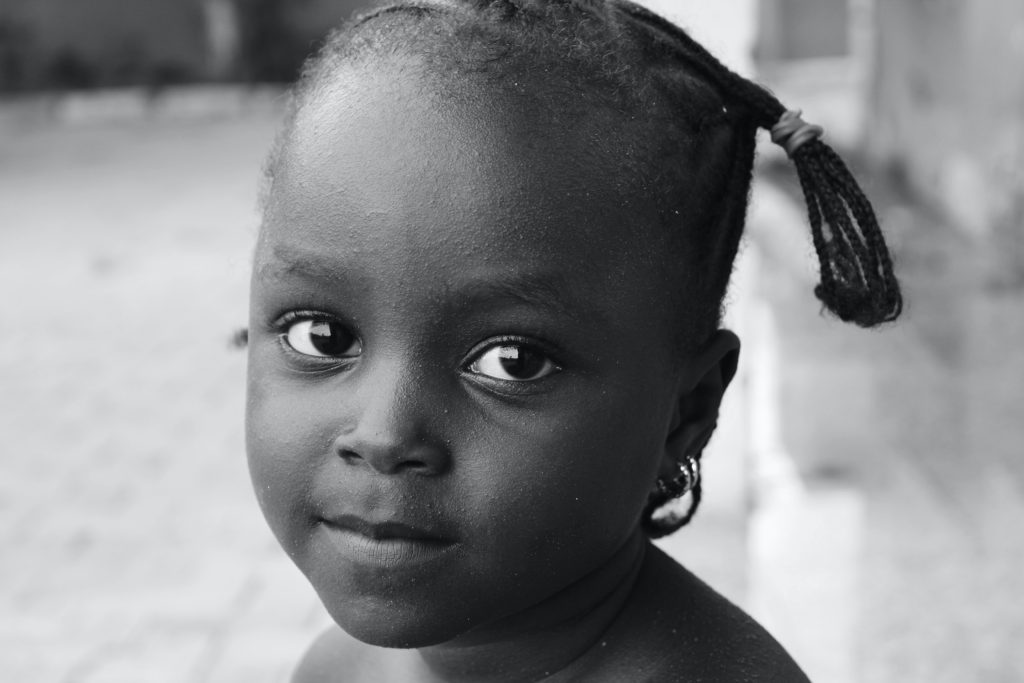 Doe eyed and velvet skinned, six years old Somalian child looks into the camera with steady compassion in her eyes.