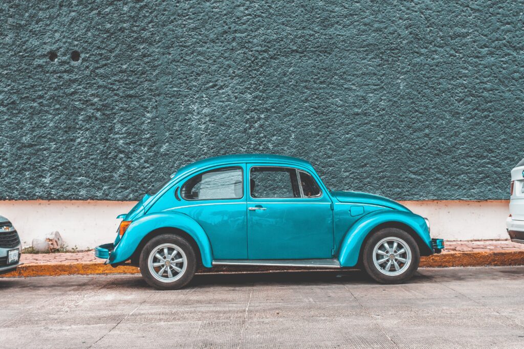 A shiny, turquoise Volkswagen beetle from the 1960s.