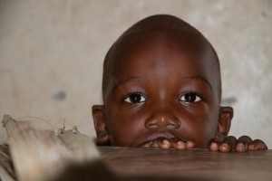 Young African boy pictured from mouth up, gazing into the camera